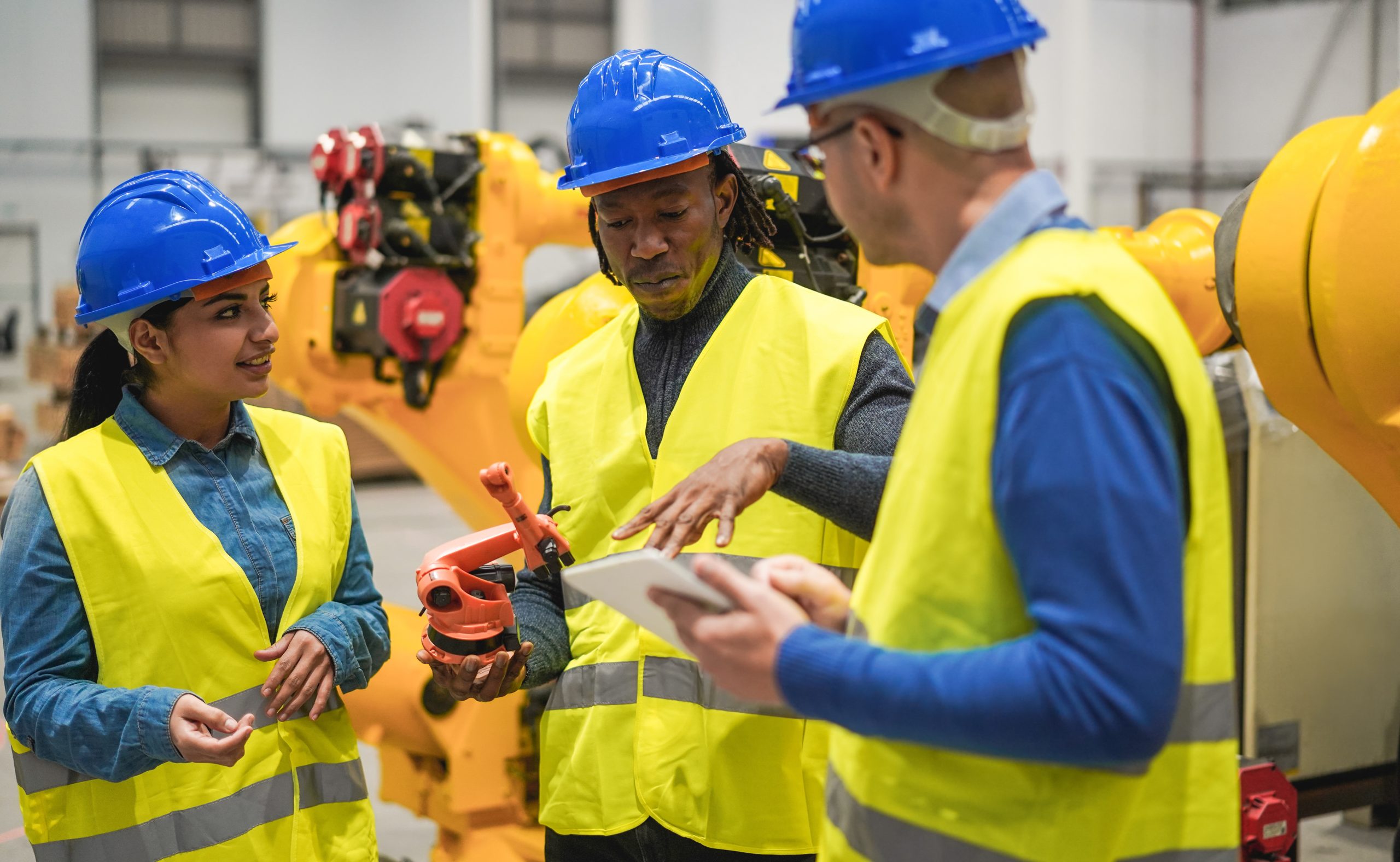 Multiracial engineers working inside robotic factory – Soft focus on african man face